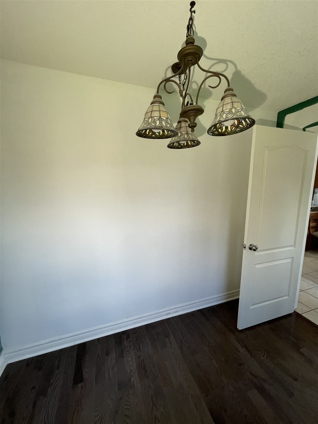 Finished office with painted walls, a white panel door, a hanging light fixture and dark hardwood flooring
